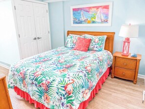 A bedroom with a bed, a nightstand, a lamp, and a door.