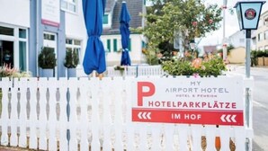 A hotel sign with a white picket fence and a red banner.