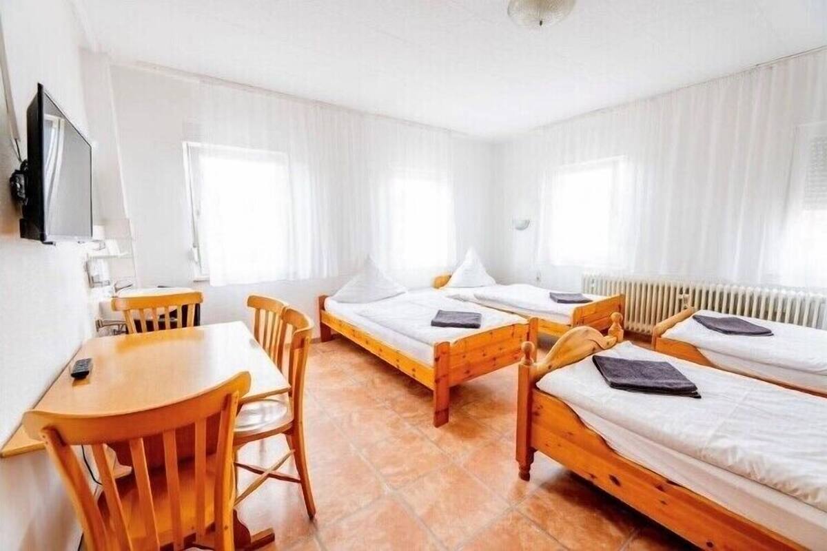 A room with two wooden beds, a wooden table, and chairs.