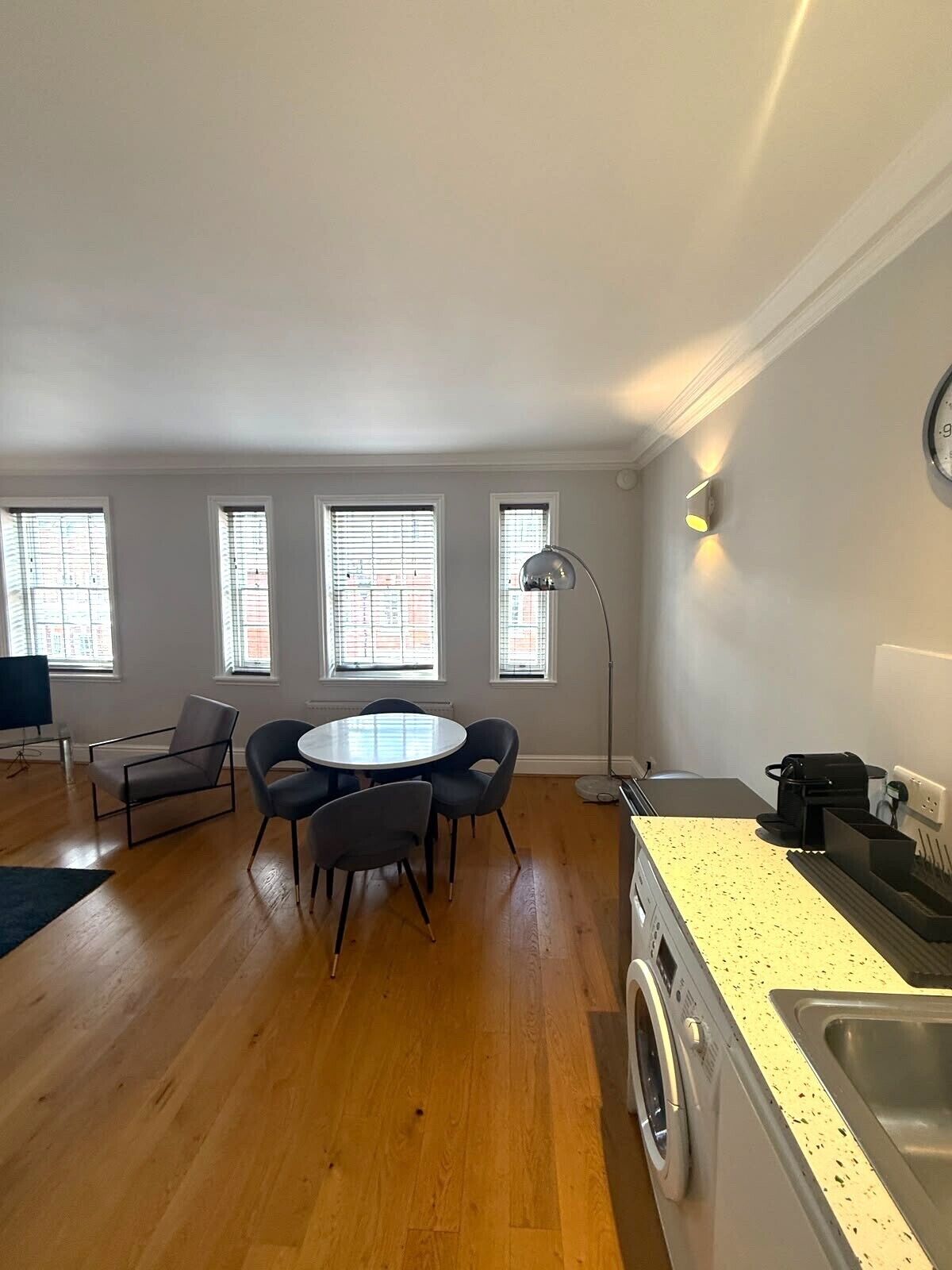 A spacious living area with a round dining table, a sofa, and a washing machine.
