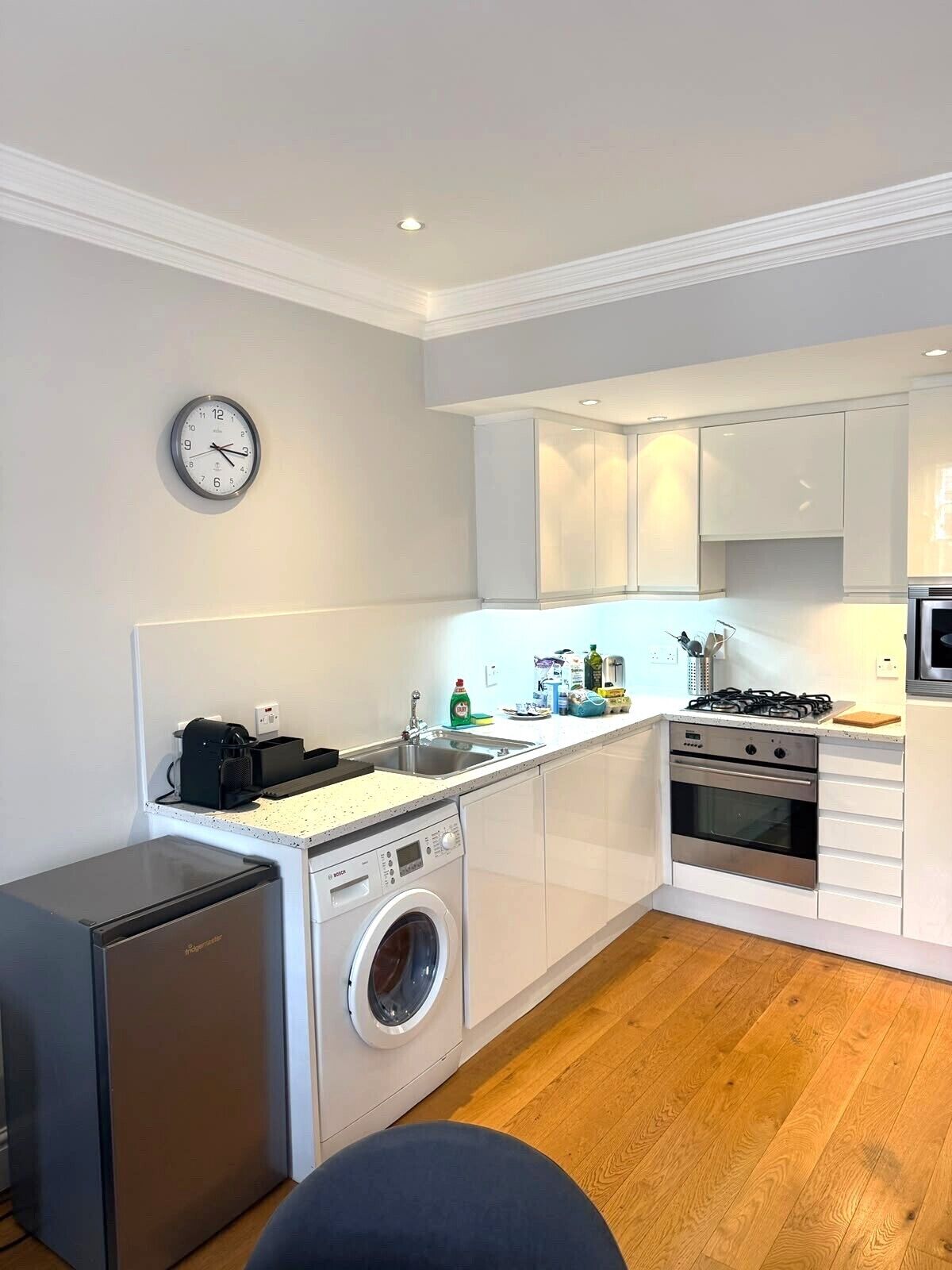A compact kitchen with a washing machine, a small refrigerator, a sink, and a stove.