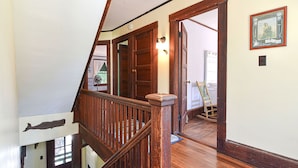 A wooden staircase with a handrail leading to a landing. A door with a light fixture is visible in the background.