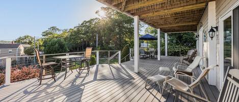 A wooden deck with outdoor furniture, including chairs and a table, and a covered area with a railing.