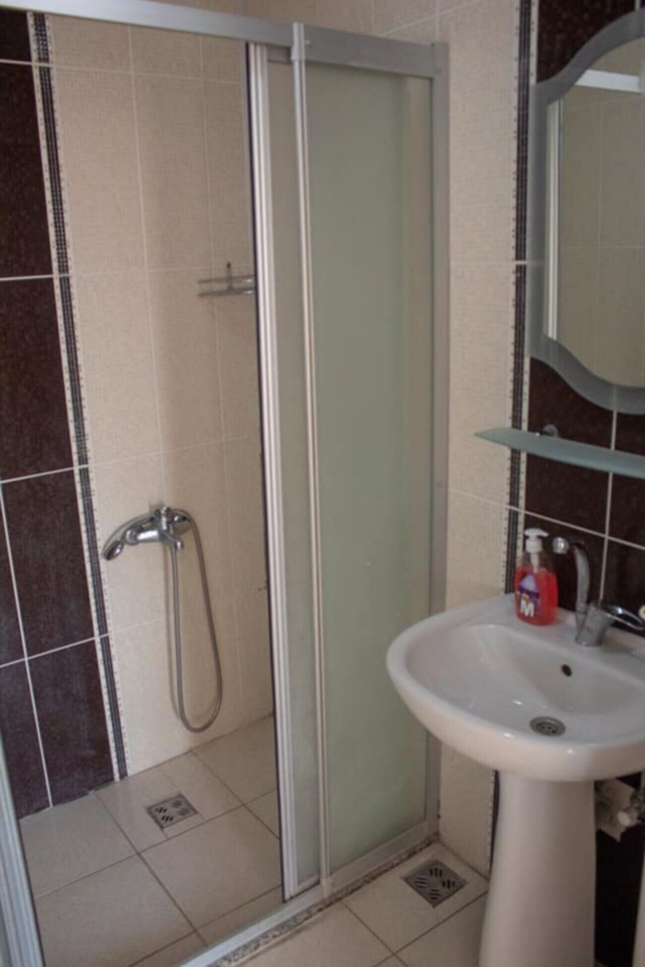 A bathroom with a glass-enclosed shower, a sink, and a mirror.