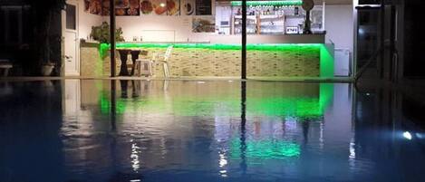 Una piscina interior con zona de bar, que incluye una barra y asientos.