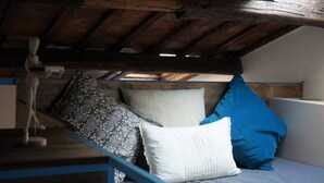 A loft-style bedroom with a sloped ceiling, a wooden bed frame, and a variety of pillows.