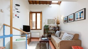 A living room with a sofa, a coffee table, a TV, a bookshelf, and a window.