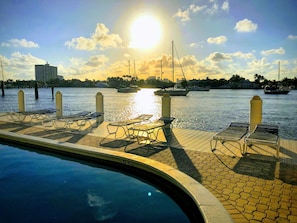 Relax by the pool with sun loungers along the waterfront promenade, overlooking a marina and city views.