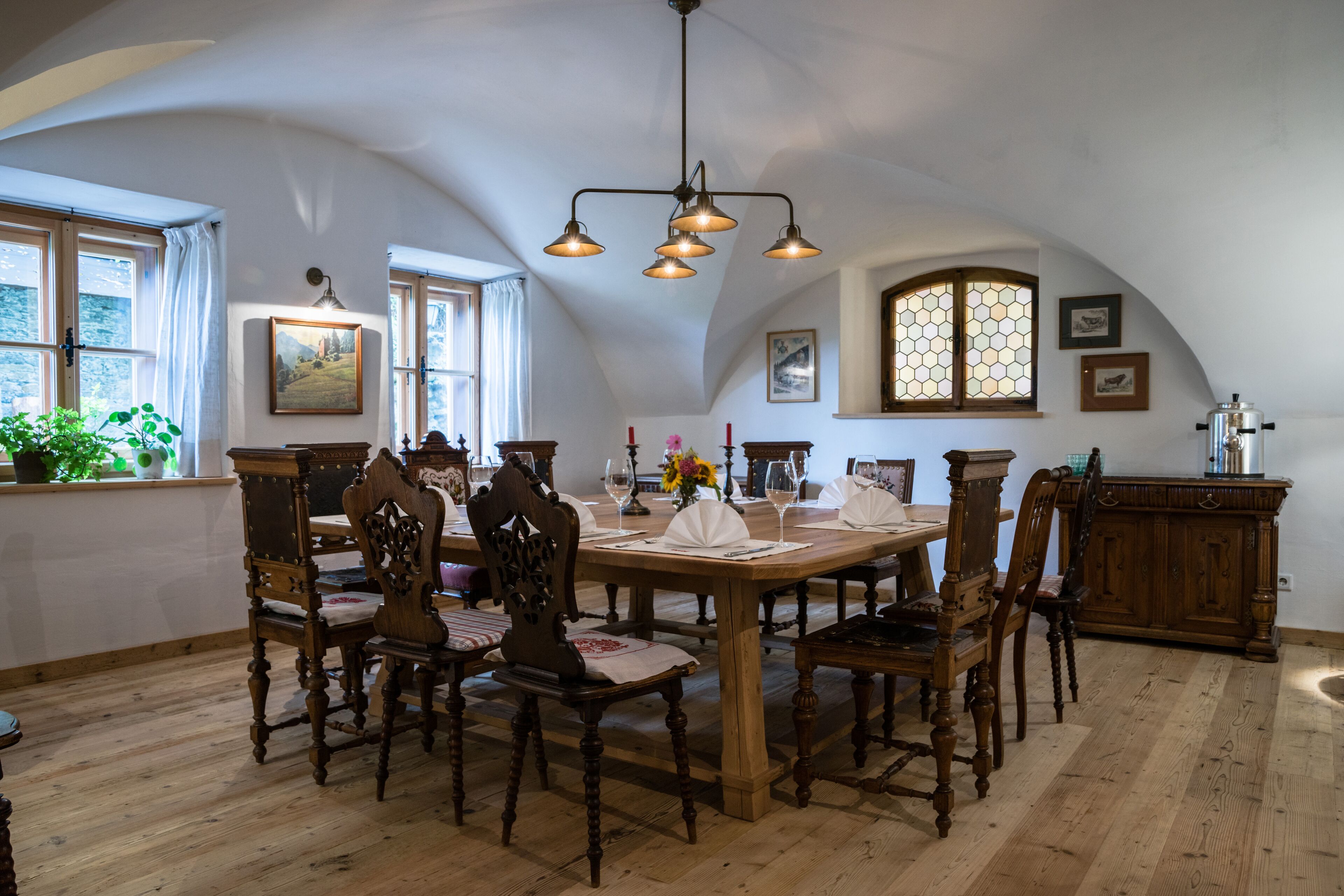 A dining room with a large wooden table, ornate chairs, and a chandelier.