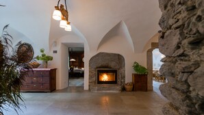 Una chimenea de piedra con fuego, un aparador de madera y un área de comedor al fondo.