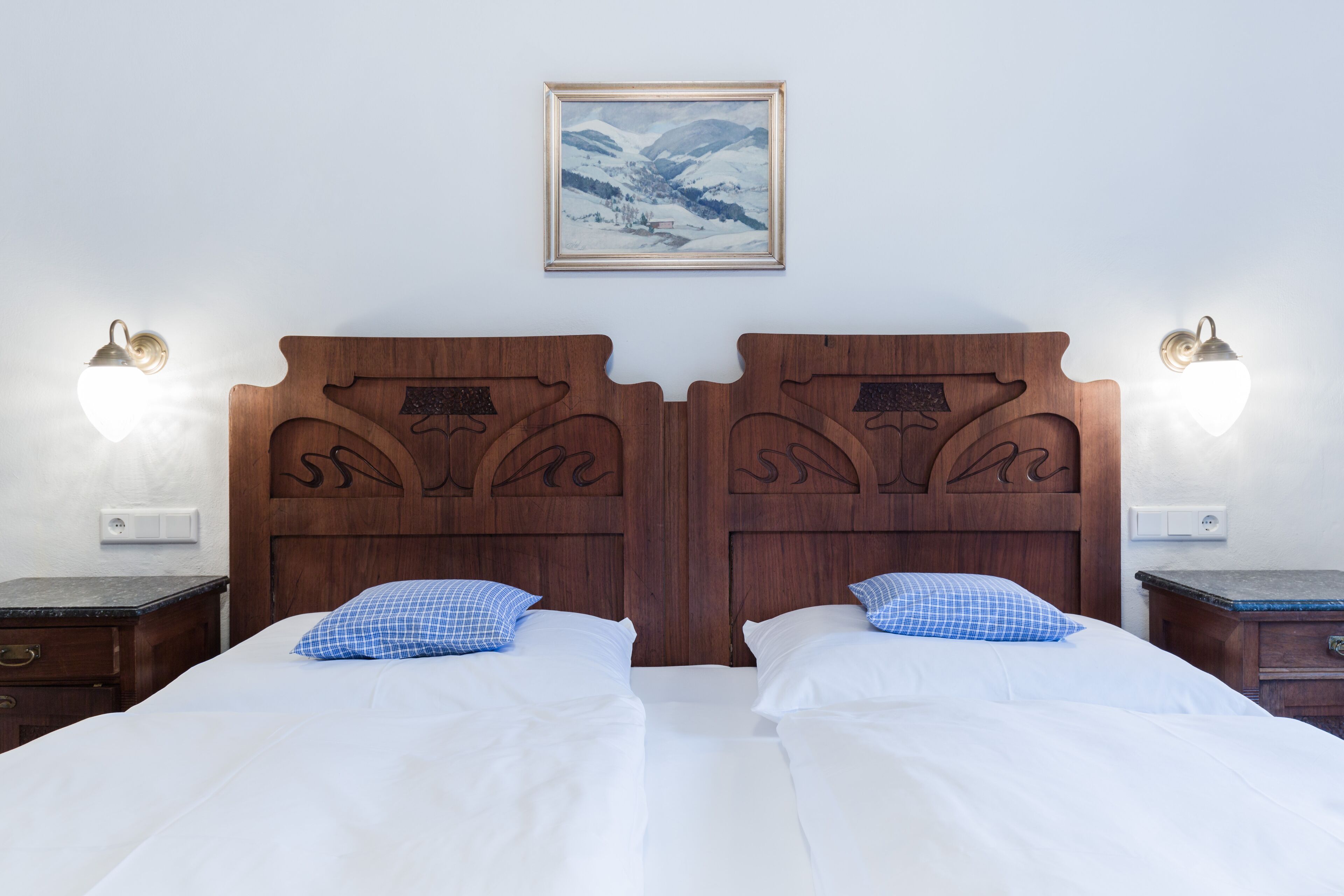 Un lit double avec une tête de lit en bois, deux tables de chevet et un tableau encadré au mur.