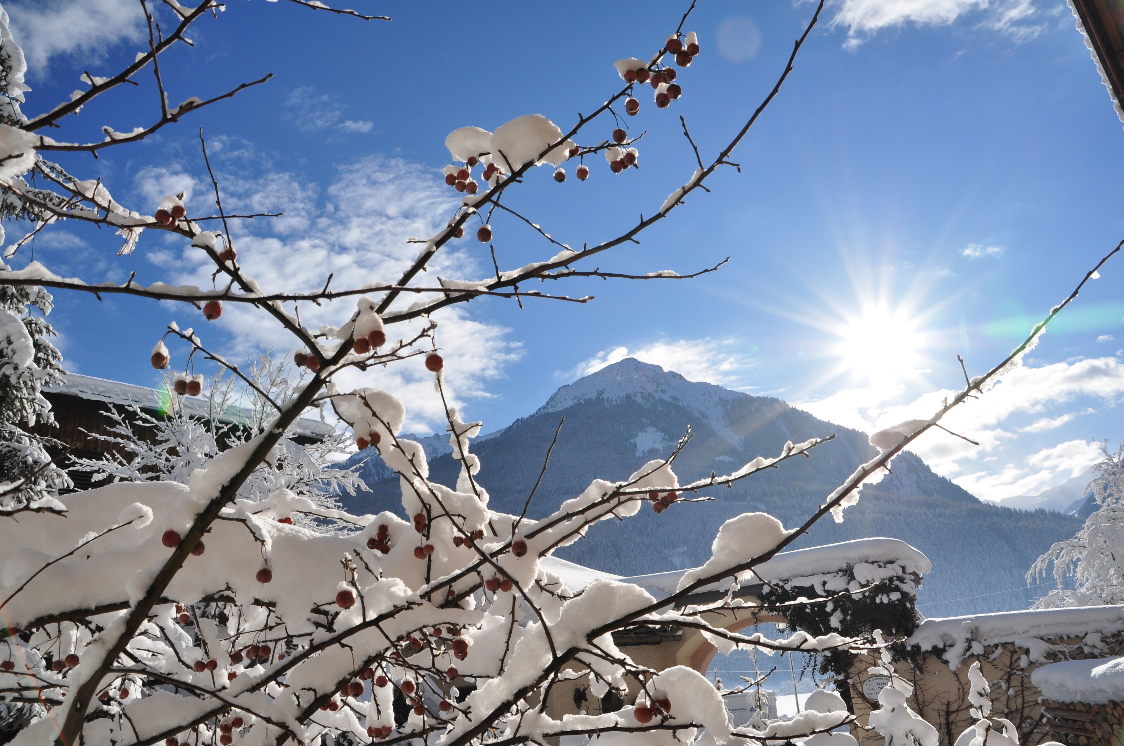A snowy mountain landscape with a clear sky and a bright sun.