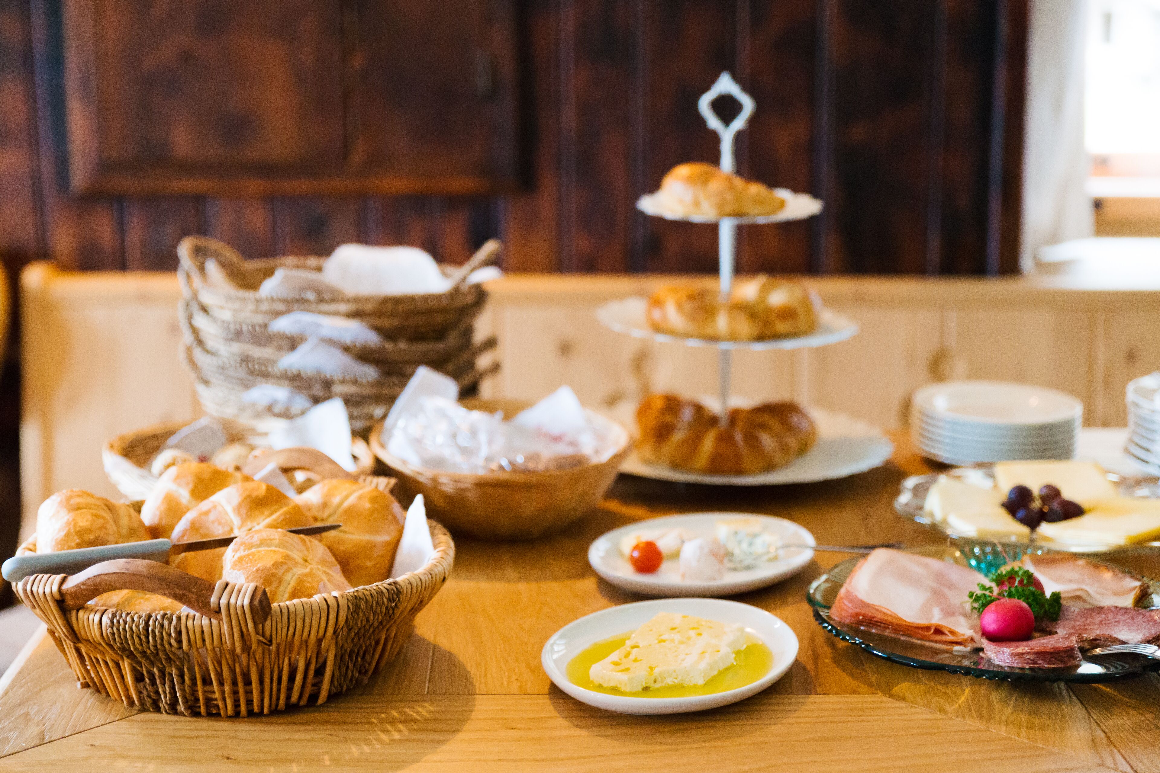 A breakfast buffet with various pastries, cheeses, and meats.