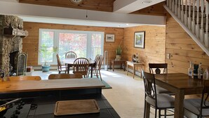 Un interior de madera acogedor con comedor, chimenea y escalera.