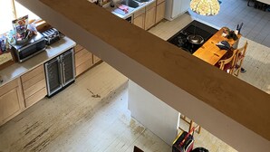 Una amplia cocina estilo loft con vigas de madera, un comedor y vista al salón inferior.