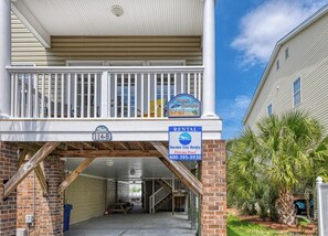 A two-story building with a balcony, a rental sign, and a private pool.