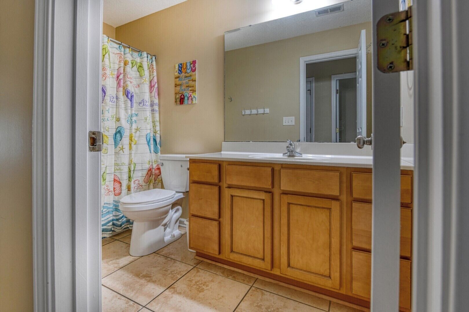 A bathroom with a toilet, wooden cabinets, a sink, and a mirror.