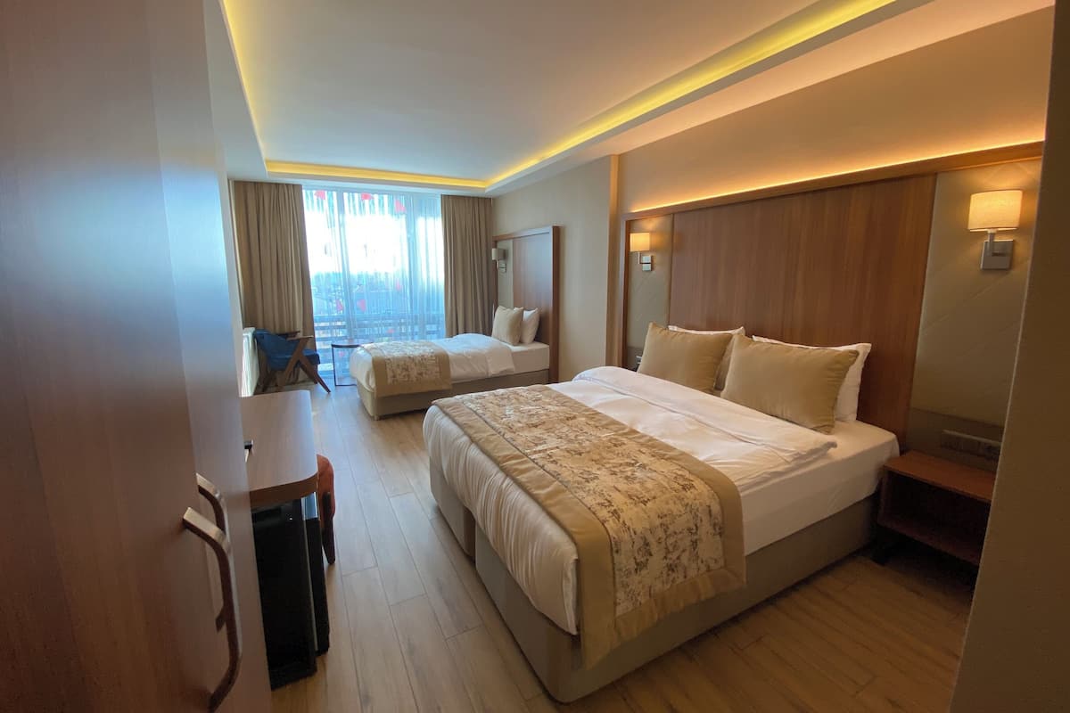 A hotel room with two beds, a desk, and a view of the city.