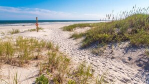 Ein Sandstrand mit Dünen und einem Rettungsturm.