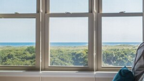Ein Zimmer mit großem Fenster, das einen Blick auf eine bewaldete Landschaft und ein Gewässer bietet.