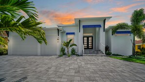 Une maison moderne avec une allée, un garage et une entrée principale avec des marches.
