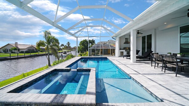 Une piscine dotée d’un toit en verre, entourée d’un patio aménagé avec du mobilier d’extérieur.