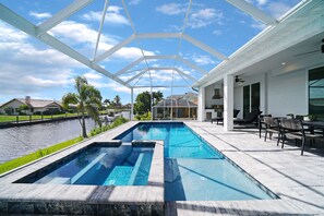 A swimming pool with a glass ceiling, surrounded by a patio area with outdoor furniture. - Waterfront Pool Home With Dock and Spa (Punta Gorda)