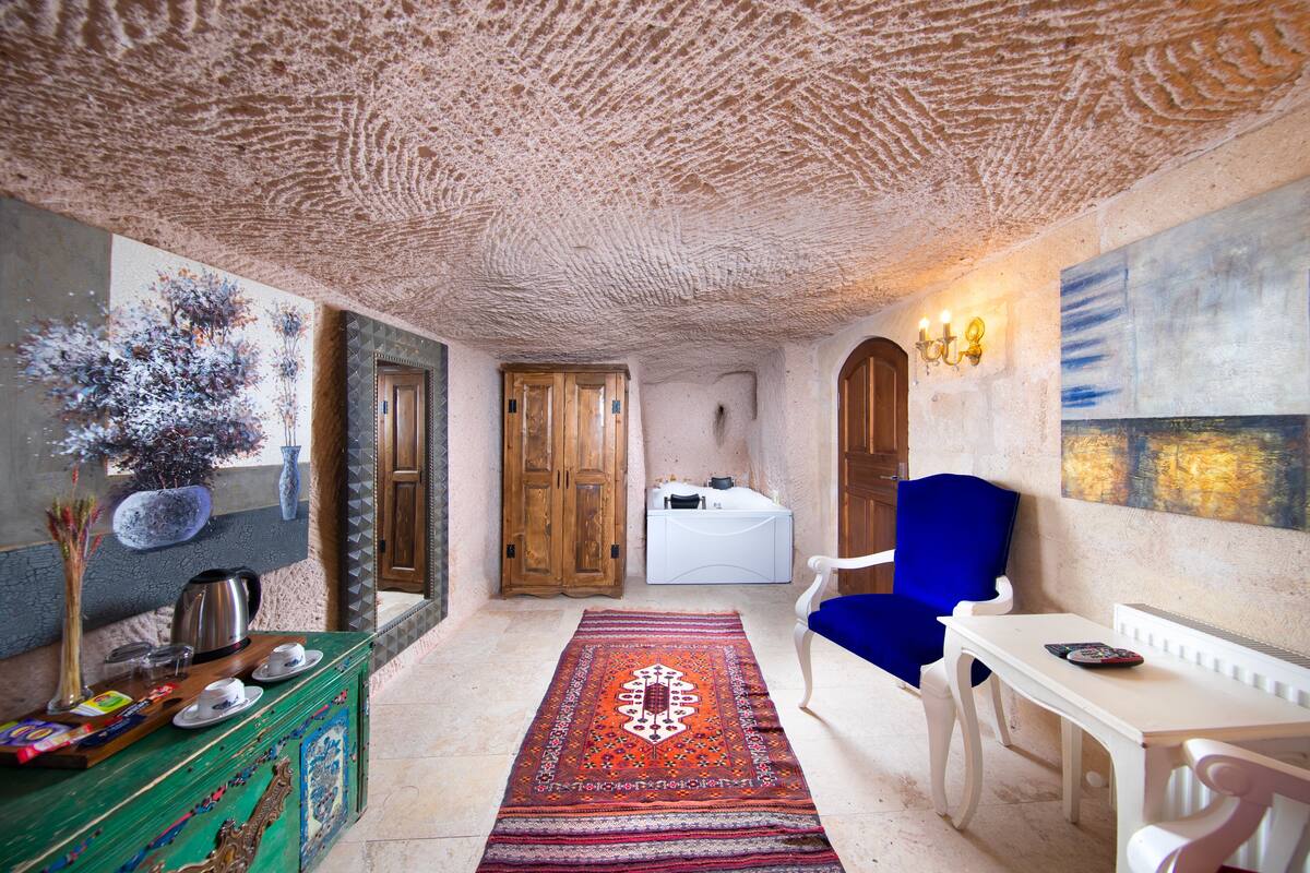 Une pièce avec un tapis à motifs, une chaise bleue, une table blanche et un meuble en bois.