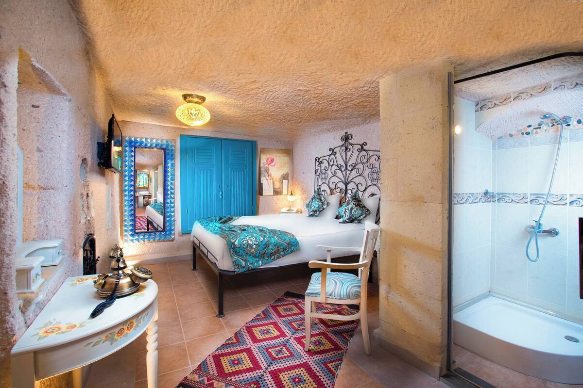 Une chambre à coucher comprenant un lit, une chaise, une table de chevet, un miroir et un espace douche.