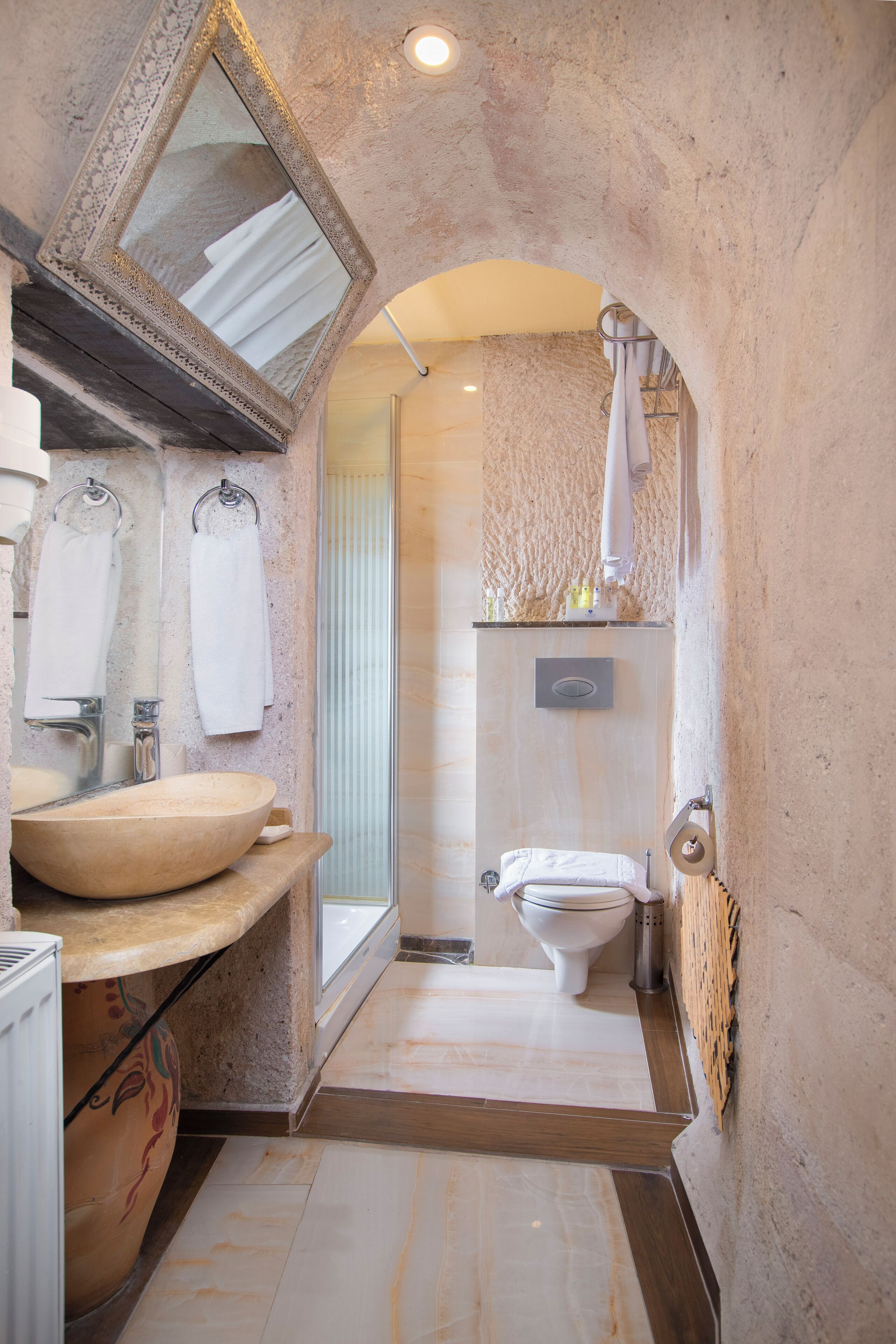 Un baño con un espejo grande, un tocador de madera, un lavabo, un inodoro y una zona de ducha.