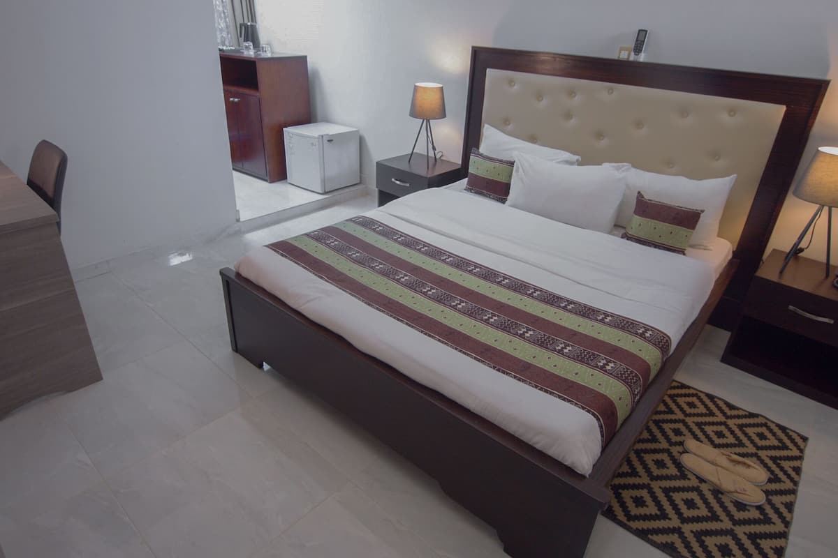 Een hotelkamer met een bed, nachtkastjes, een bureau en een kledingkast.