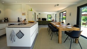 A modern kitchen with a central island, dining table with chairs, and a view of the outdoors.