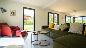 A modern living room with a red chair, green sofa, and a small round table.