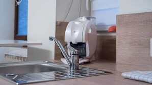 Et moderne køkken med en stålvask, en hvid kaffemaskine og en træbordplade.