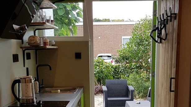 Une cuisine moderne dotée d’un îlot central intégré, d’un évier et d’une fenêtre donnant sur un patio aménagé avec du mobilier d’extérieur.