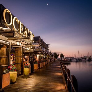 Un bar frente al agua con una terraza de madera y vistas al puerto deportivo.