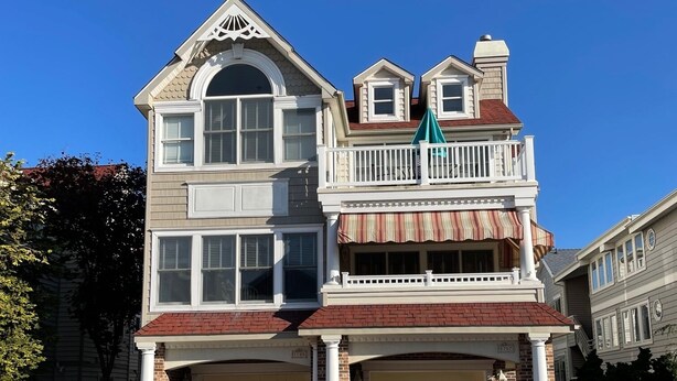 A two-story house with a garage, a balcony, and a small attached garage.