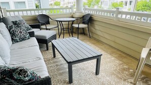 A covered outdoor seating area with a sofa, chairs, and a table.