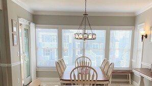 A dining area with a marble table, white chairs, and a hanging light fixture.