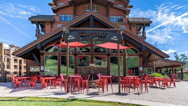 A building with a ski resort name, outdoor seating with red chairs, and a clear sky. - Great Views, Summer Resort Activities! (Durango)