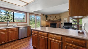 A modern kitchen with wooden cabinets, a dishwasher, a large island, and a fireplace. - Great Views, Summer Resort Activities! (Durango)