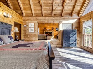 A log cabin bedroom with a bed, dresser, and fireplace. - ER16 - Mountain Blessing | Great location - Close to town! (Pigeon Forge)