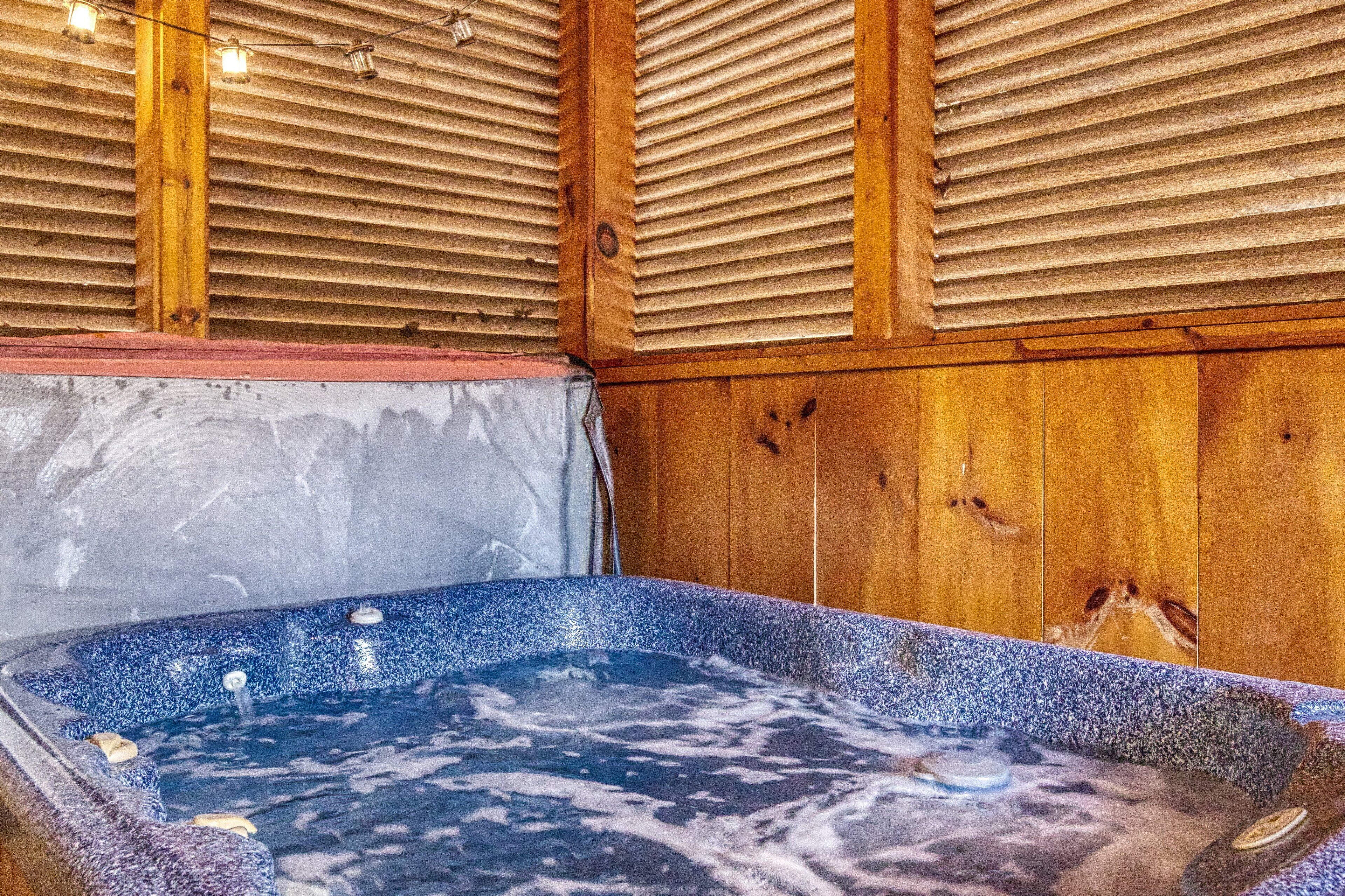 Un bain à remous avec un intérieur en bois, un plafond en bois avec des lambris et un mur en pierre.