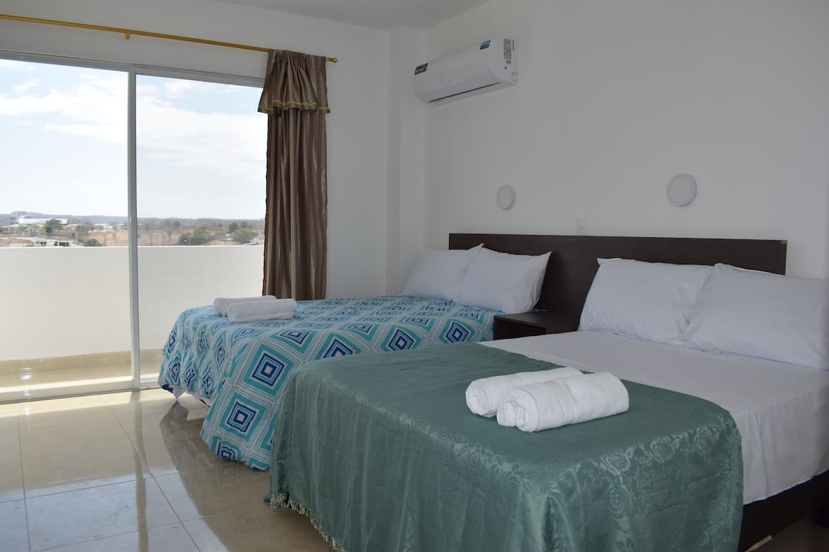 Une chambre d’hôtel avec deux lits, une grande fenêtre donnant sur un beau paysage et un climatiseur fixé au mur.