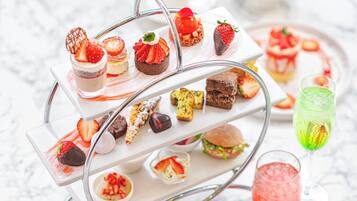 Un présentoir à étages garni de divers desserts et boissons, notamment des fraises, du chocolat et un cocktail vert.