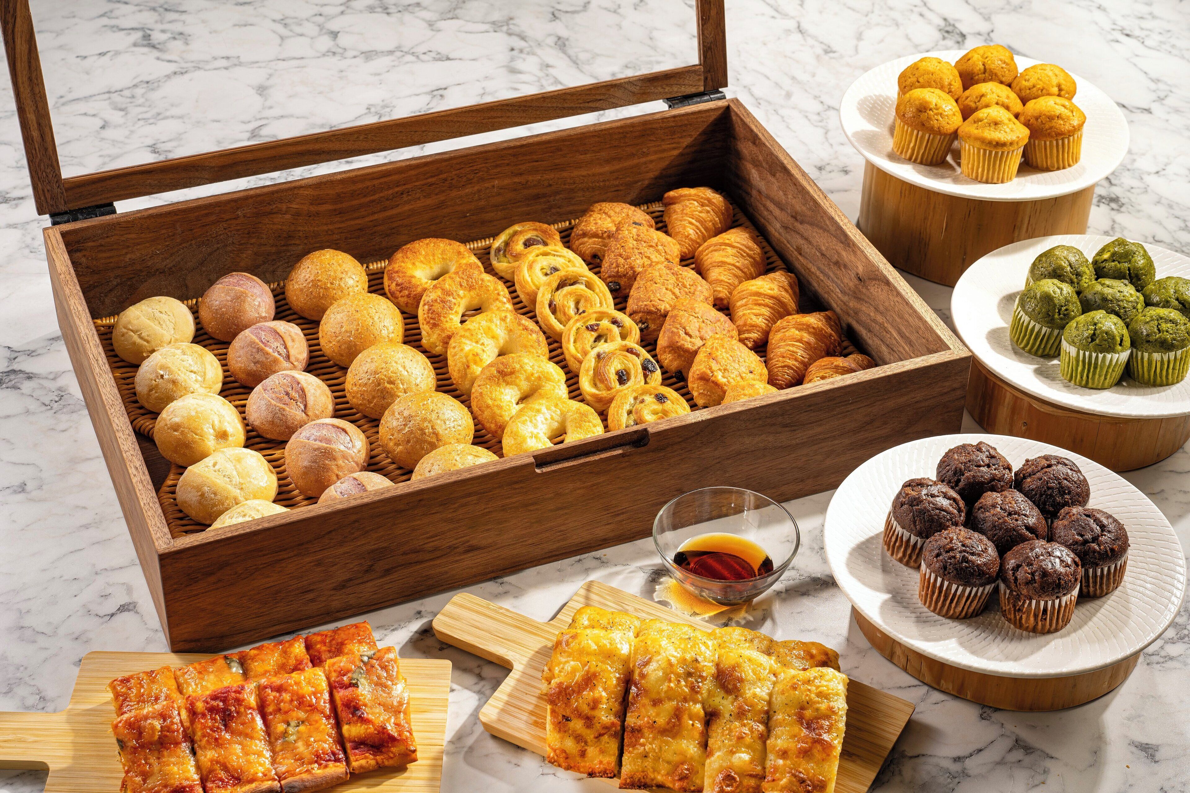 Une boîte en bois remplie de diverses pâtisseries, une assiette de muffins et une assiette de muffins au chocolat.