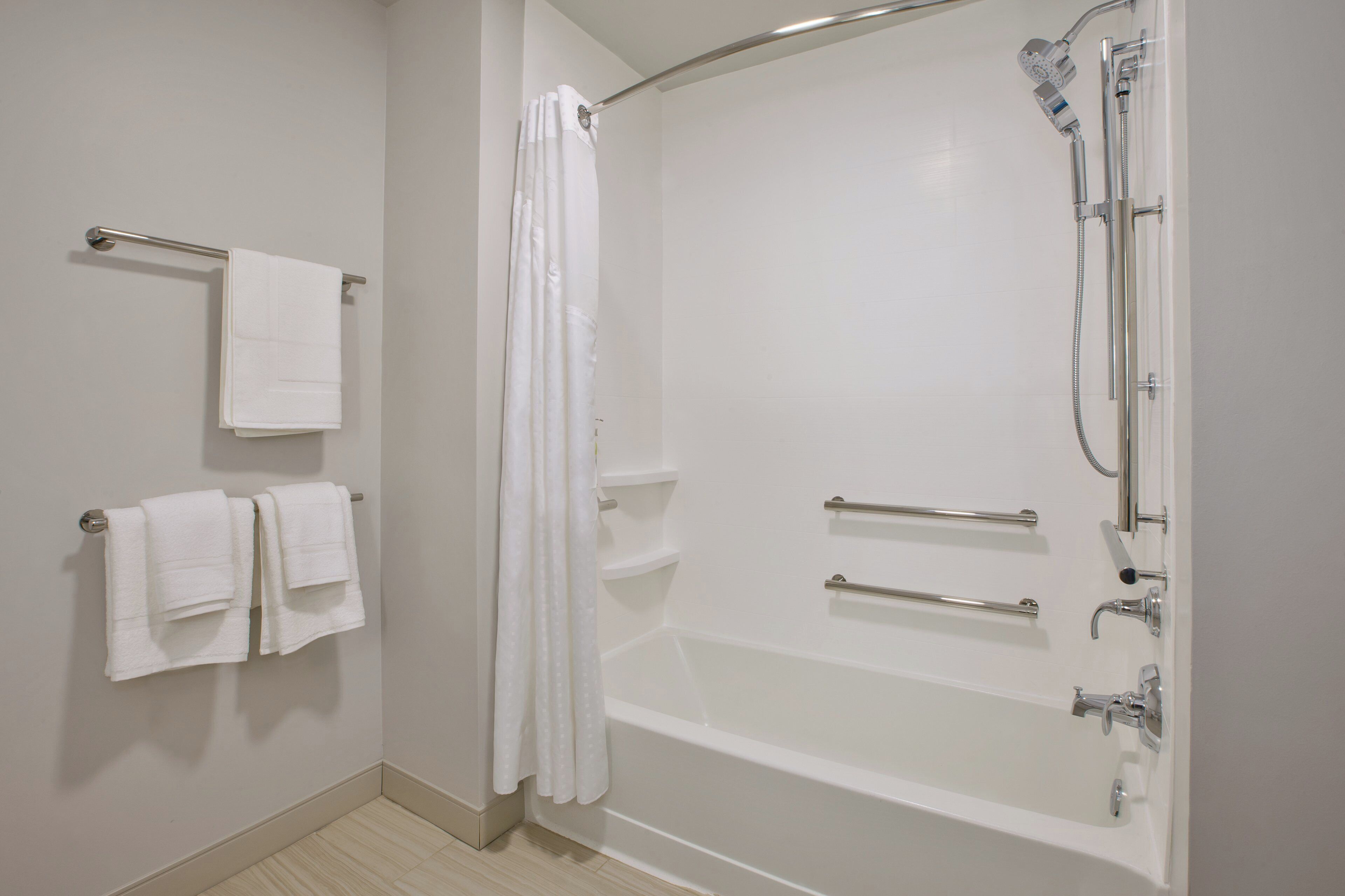 Ein modernes Badezimmer mit begehbarer Dusche, einer Badewanne und zwei Handtuchhaltern mit weißen Handtüchern.