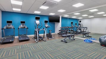 Un gimnasio con cintas de correr, elípticas y pesas libres.