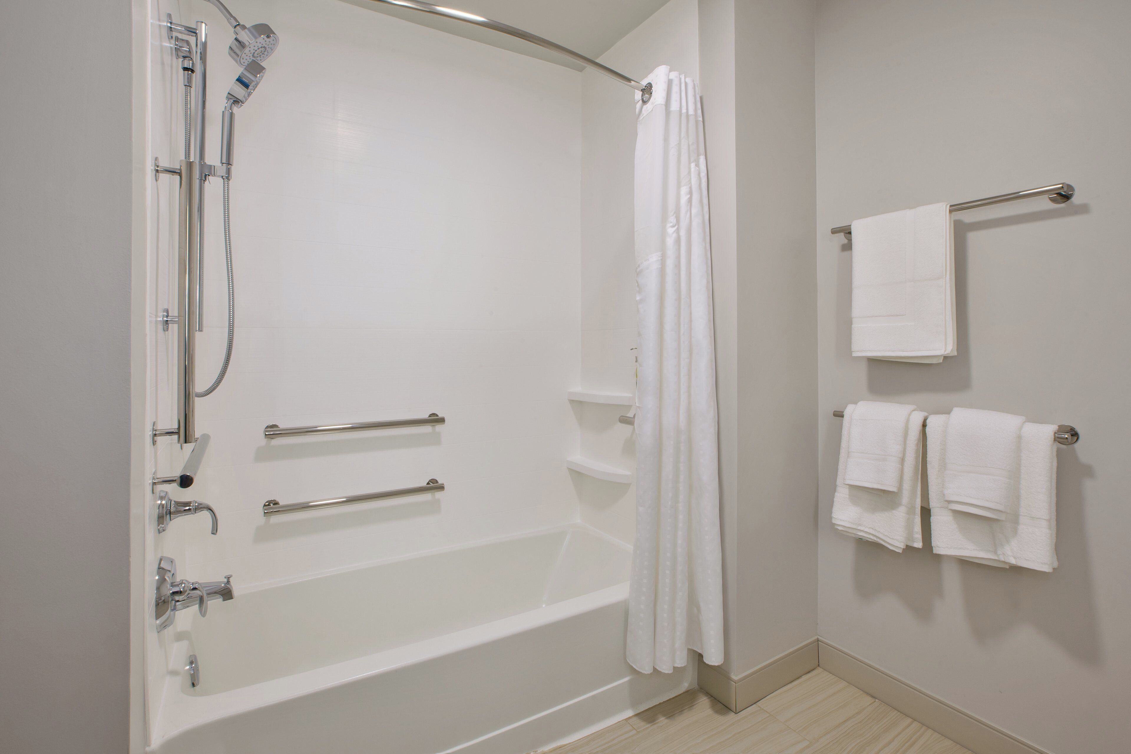 Un baño moderno con bañera, ducha y barras de apoyo.