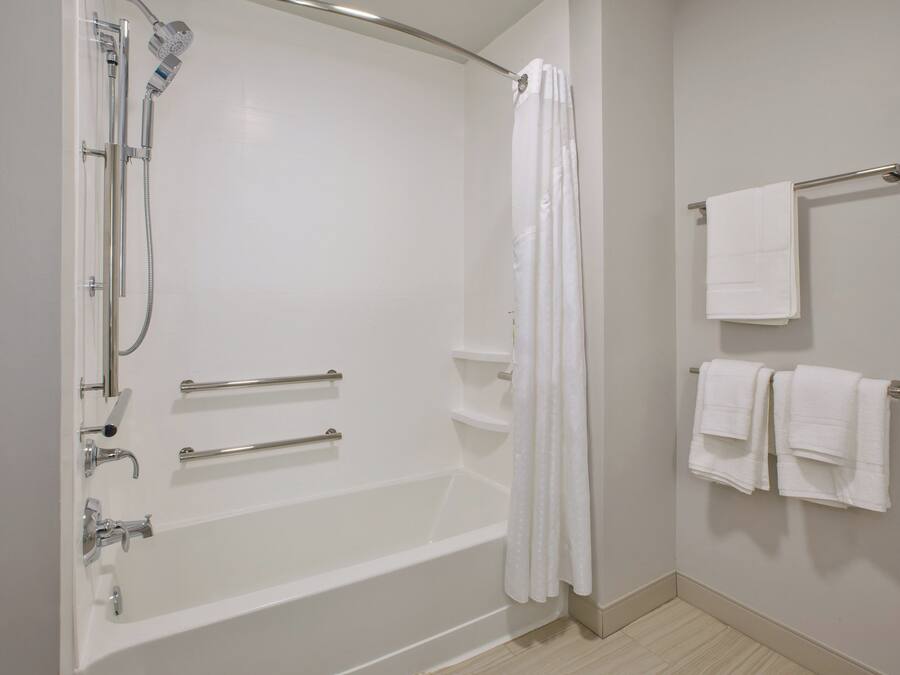 Un baño moderno con bañera, ducha y barras de apoyo.